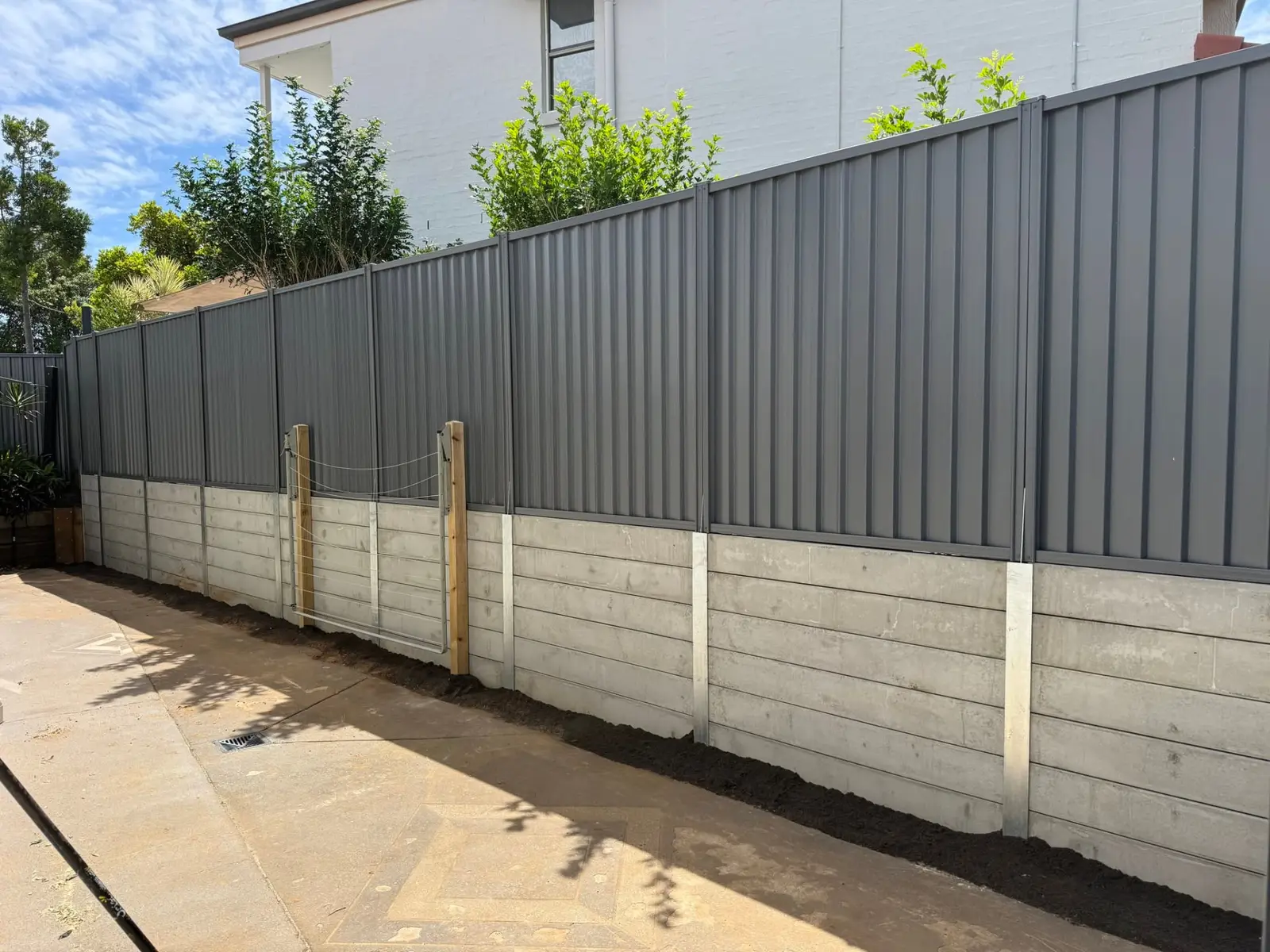 Grey Colorbond fence built on top of a concrete sleeper retaining wall at a Brisbane property
