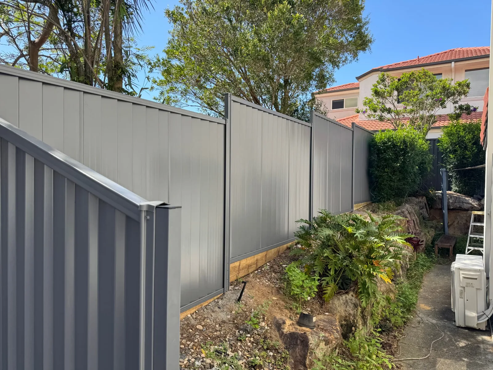 Colorbond boundary fence following sloping terrain beside a Wynnum West home
