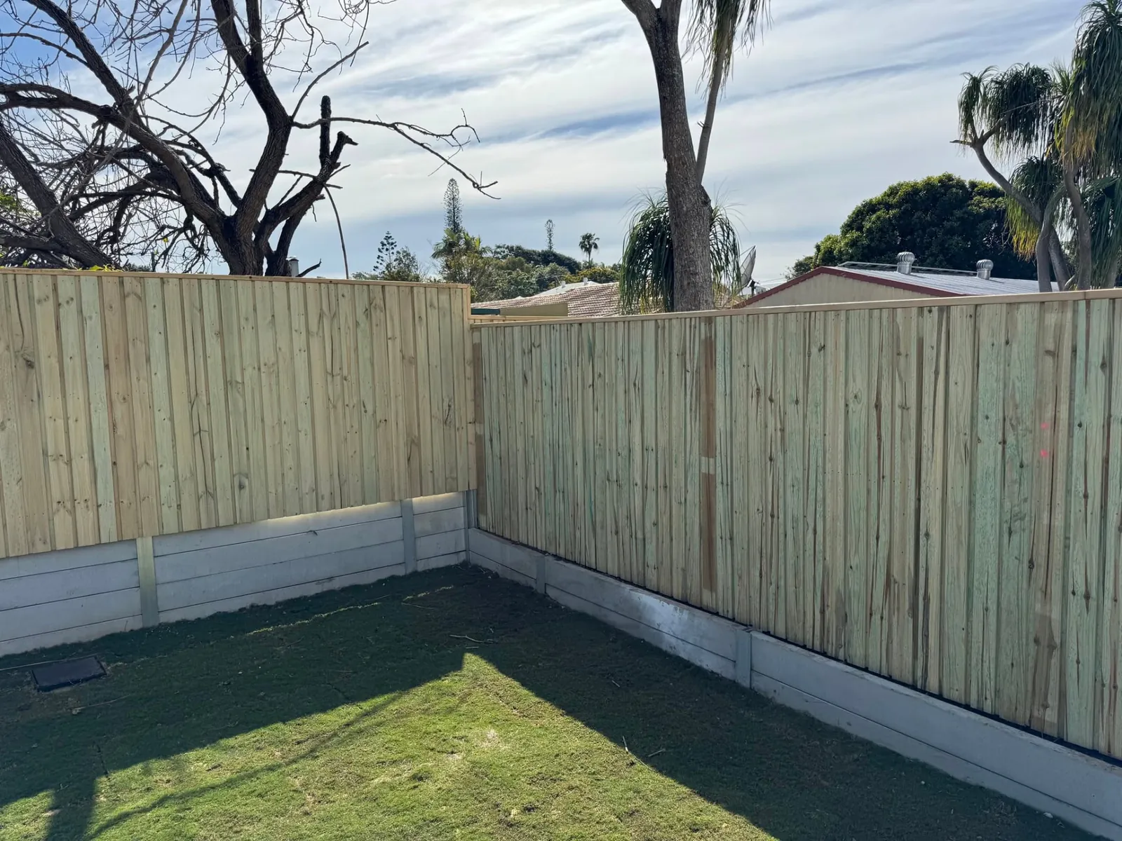 Treated pine boundary fence installed above an existing concrete retaining wall in Wynnum